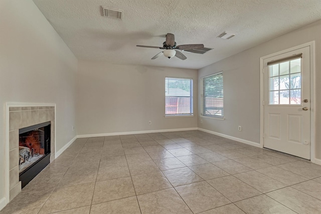 unfurnished living room featuring a tile fireplace, a textured ceiling, ceiling fan, and light tile patterned flooring