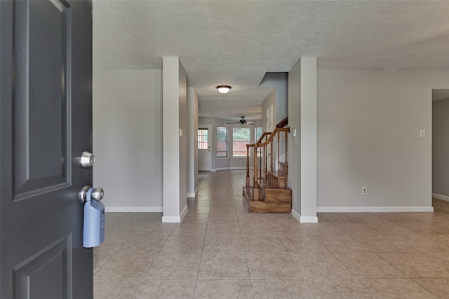 foyer with ceiling fan, light tile patterned floors, and a textured ceiling