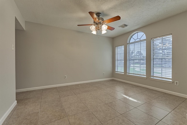 tiled empty room featuring ceiling fan and a textured ceiling