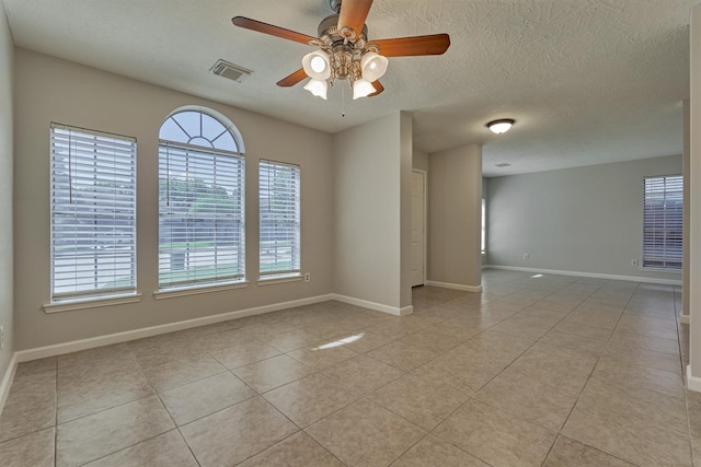 tiled spare room with a textured ceiling and ceiling fan