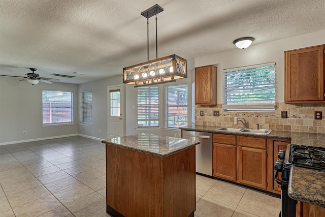 kitchen with decorative backsplash, gas stove, pendant lighting, dishwasher, and a kitchen island