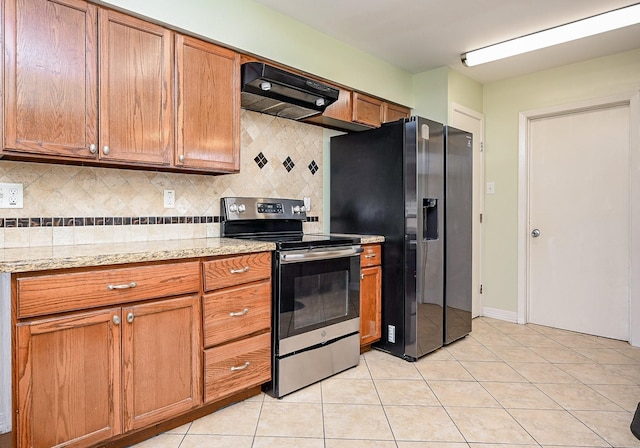 kitchen with light stone countertops, tasteful backsplash, light tile patterned flooring, stainless steel appliances, and extractor fan