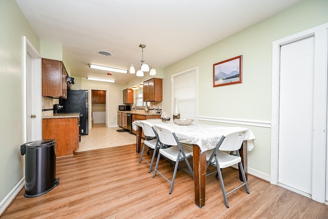 dining room featuring light wood-type flooring and an inviting chandelier