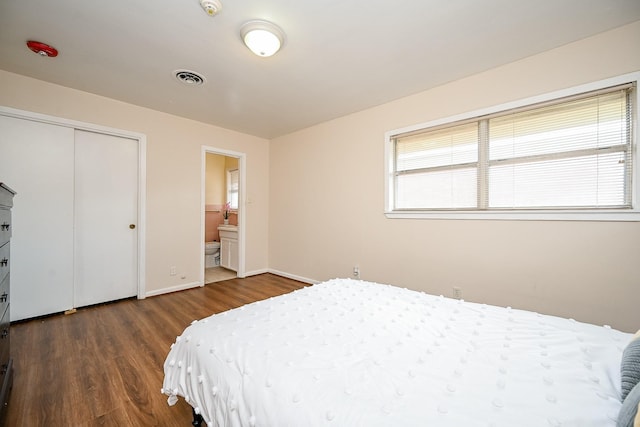 bedroom featuring ensuite bathroom, a closet, and dark wood-type flooring