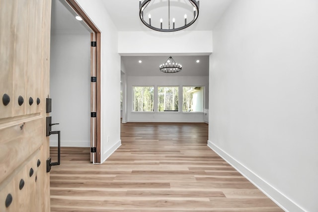 hall with light hardwood / wood-style flooring and a chandelier