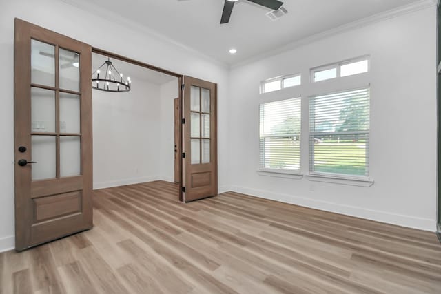 empty room with ceiling fan with notable chandelier, light hardwood / wood-style flooring, and ornamental molding