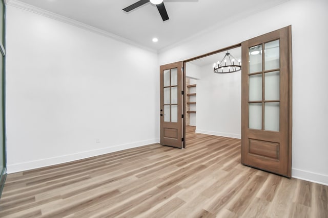 empty room with crown molding, french doors, ceiling fan with notable chandelier, and light wood-type flooring