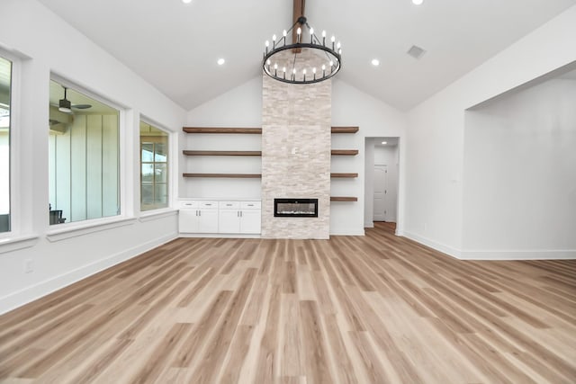 unfurnished living room featuring high vaulted ceiling, ceiling fan with notable chandelier, built in features, light wood-type flooring, and a fireplace