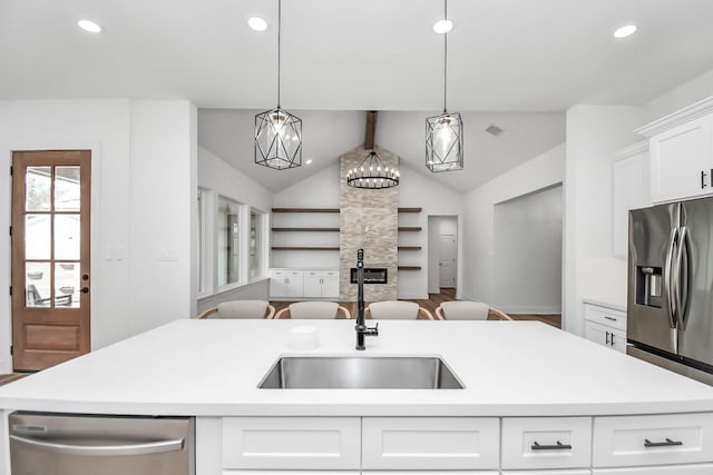 kitchen featuring sink, decorative light fixtures, a kitchen island with sink, white cabinets, and appliances with stainless steel finishes