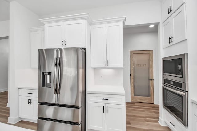 kitchen featuring white cabinets, light hardwood / wood-style floors, and appliances with stainless steel finishes