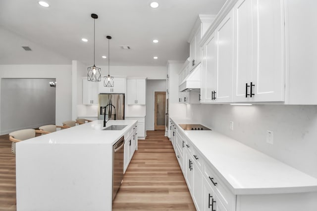 kitchen with a kitchen island with sink, white cabinets, decorative light fixtures, and appliances with stainless steel finishes