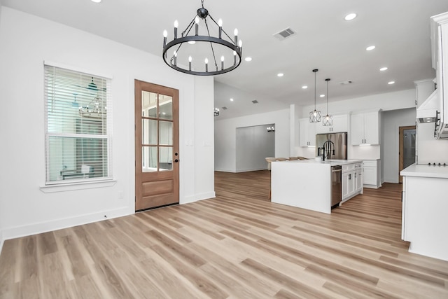 kitchen with white cabinetry, light hardwood / wood-style flooring, pendant lighting, a kitchen island with sink, and appliances with stainless steel finishes