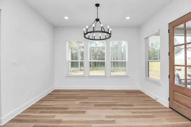 unfurnished dining area featuring light wood-type flooring and a notable chandelier