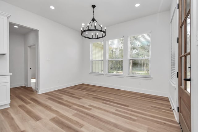 unfurnished dining area with light hardwood / wood-style flooring and a chandelier