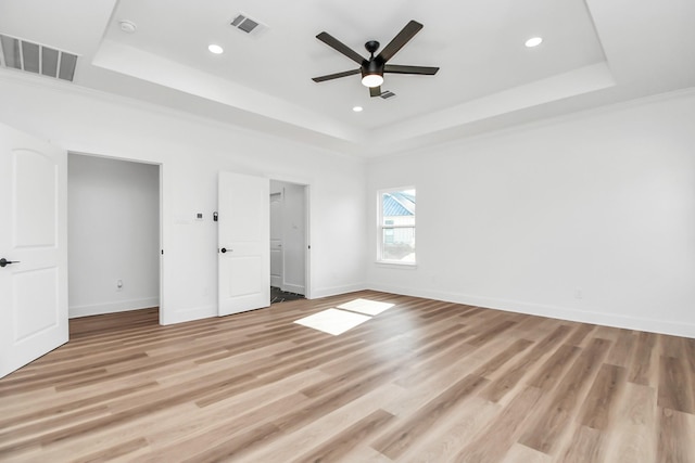 unfurnished bedroom with light wood-type flooring, a tray ceiling, ceiling fan, and crown molding