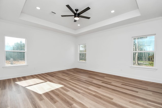 unfurnished room with hardwood / wood-style floors, ceiling fan, crown molding, and a tray ceiling