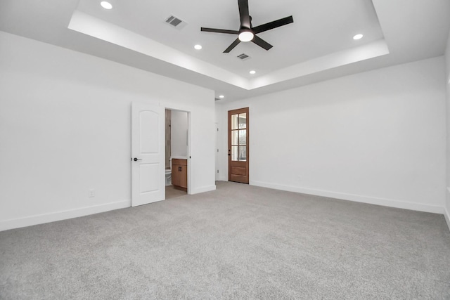 unfurnished bedroom featuring connected bathroom, a tray ceiling, and ceiling fan