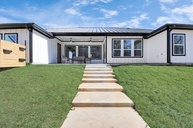 rear view of house featuring ceiling fan and a yard