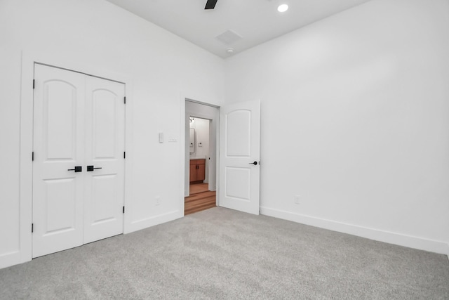 unfurnished bedroom with ceiling fan, light carpet, and a closet