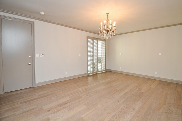 spare room featuring a chandelier, light wood-type flooring, and ornamental molding