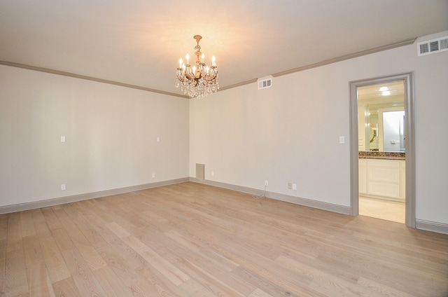 spare room featuring a chandelier, light wood-type flooring, and ornamental molding