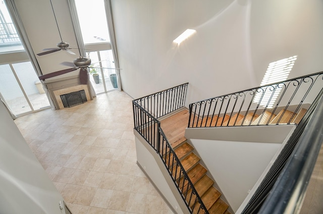 stairs with tile patterned flooring, ceiling fan, and a healthy amount of sunlight