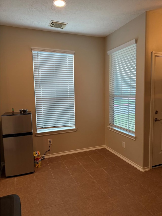 spare room with tile patterned flooring and a textured ceiling