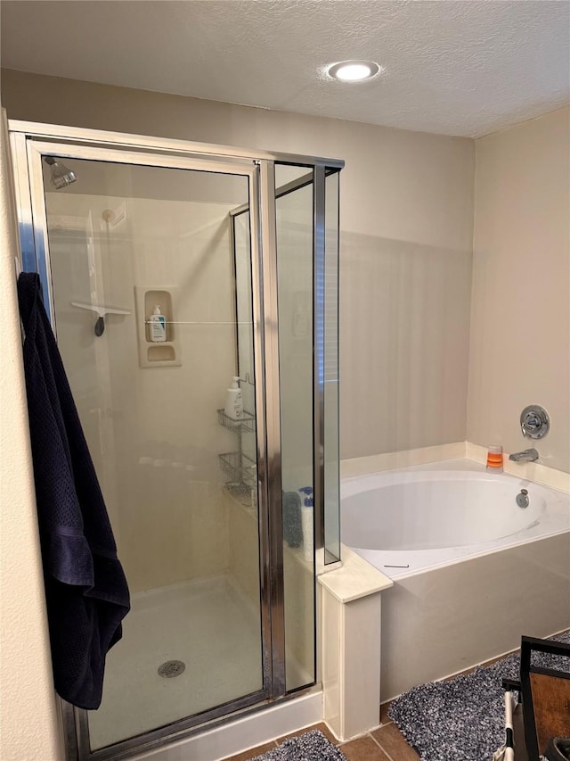 bathroom featuring tile patterned flooring, a textured ceiling, and plus walk in shower