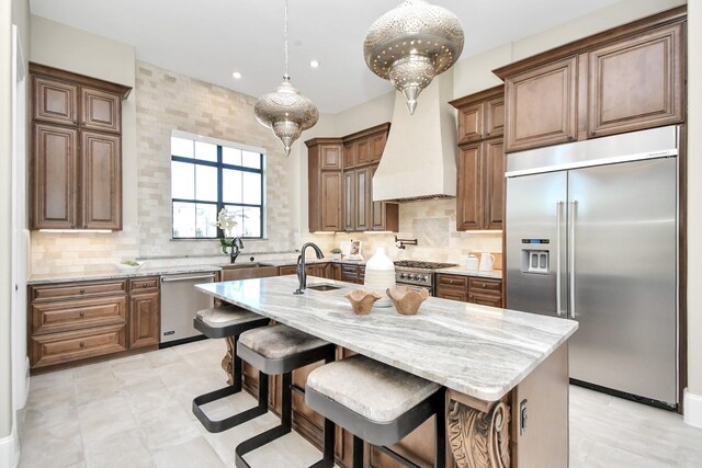 kitchen featuring hanging light fixtures, decorative backsplash, stainless steel appliances, and a kitchen island with sink