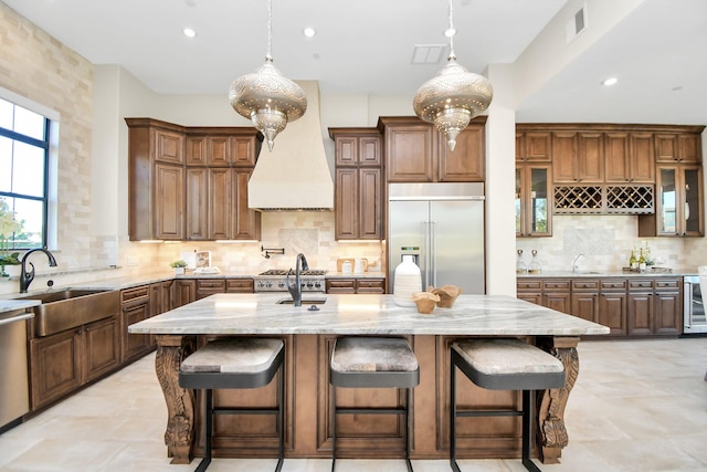 kitchen featuring backsplash, sink, stainless steel appliances, and a center island with sink