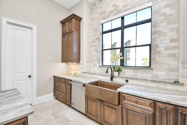 kitchen with stainless steel dishwasher, light stone counters, sink, and tasteful backsplash