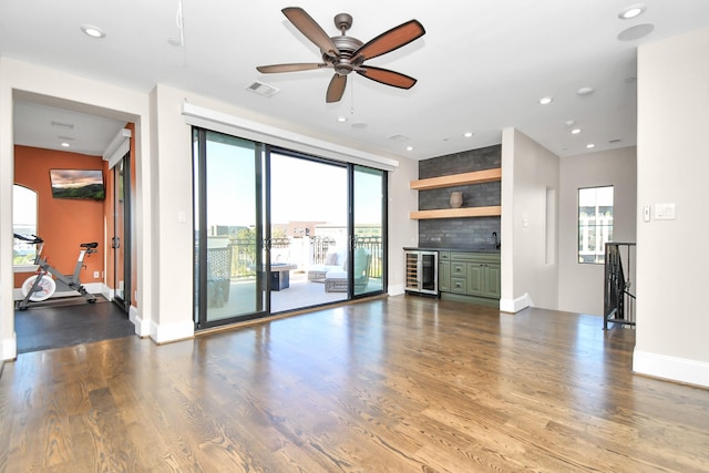 unfurnished living room featuring hardwood / wood-style floors, indoor bar, wine cooler, and ceiling fan