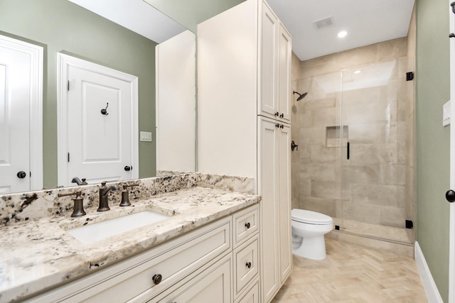 bathroom featuring parquet flooring, toilet, vanity, and walk in shower