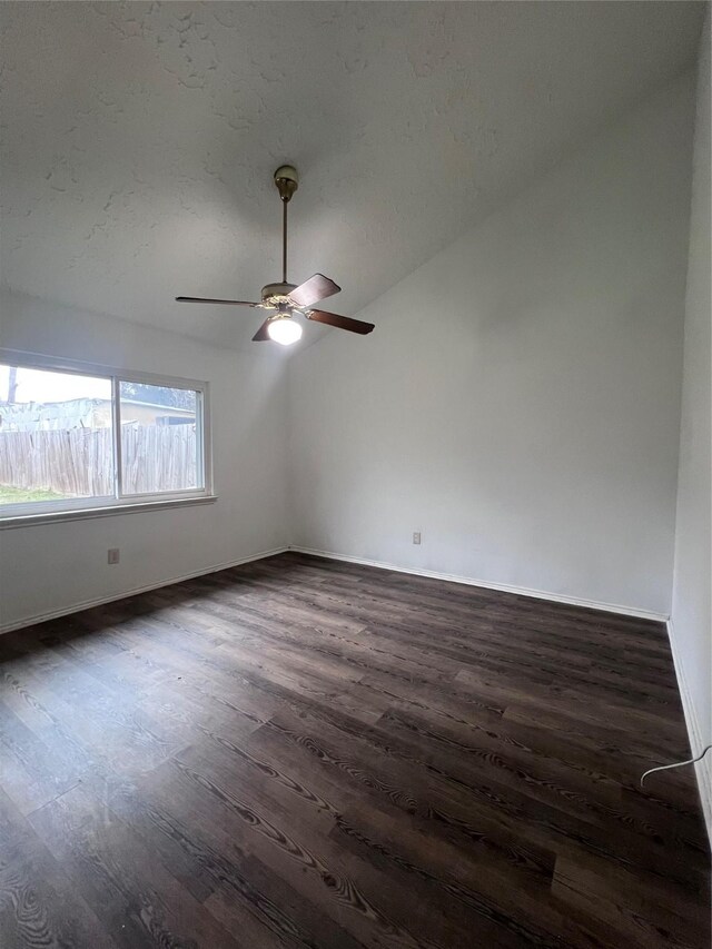 empty room with dark hardwood / wood-style flooring, vaulted ceiling, and ceiling fan