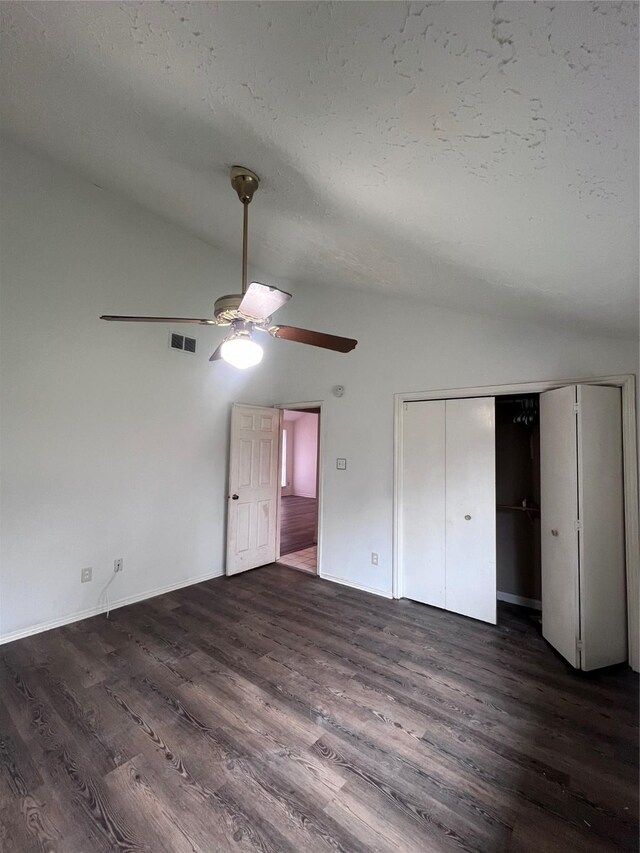 unfurnished bedroom with a closet, dark hardwood / wood-style floors, vaulted ceiling, and ceiling fan