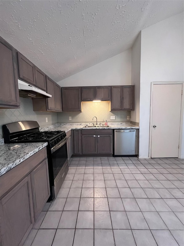 kitchen featuring dark brown cabinetry, sink, stainless steel appliances, vaulted ceiling, and light tile patterned floors