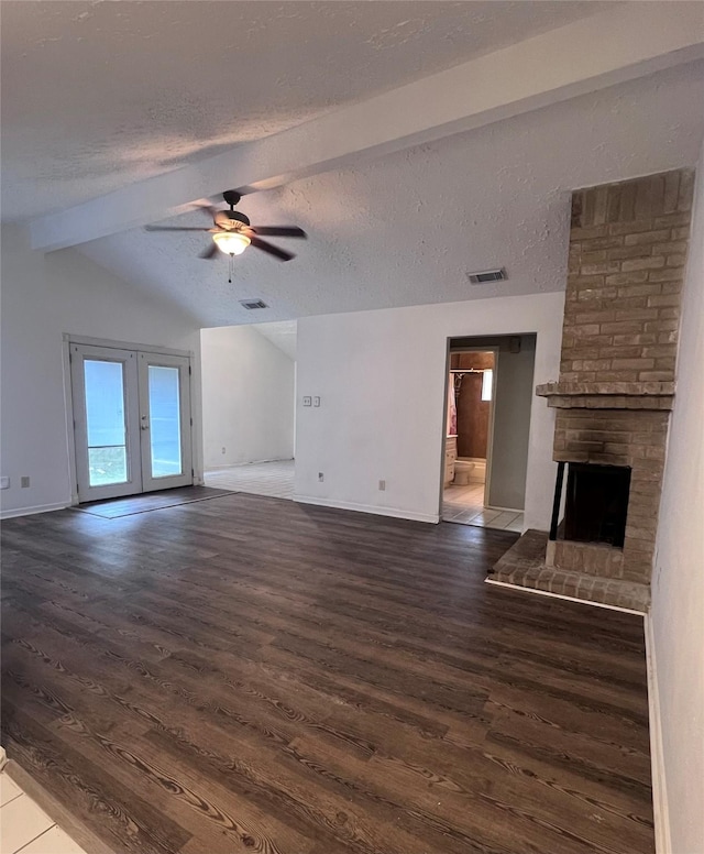 unfurnished living room featuring dark wood-type flooring, vaulted ceiling with beams, ceiling fan, a textured ceiling, and a fireplace