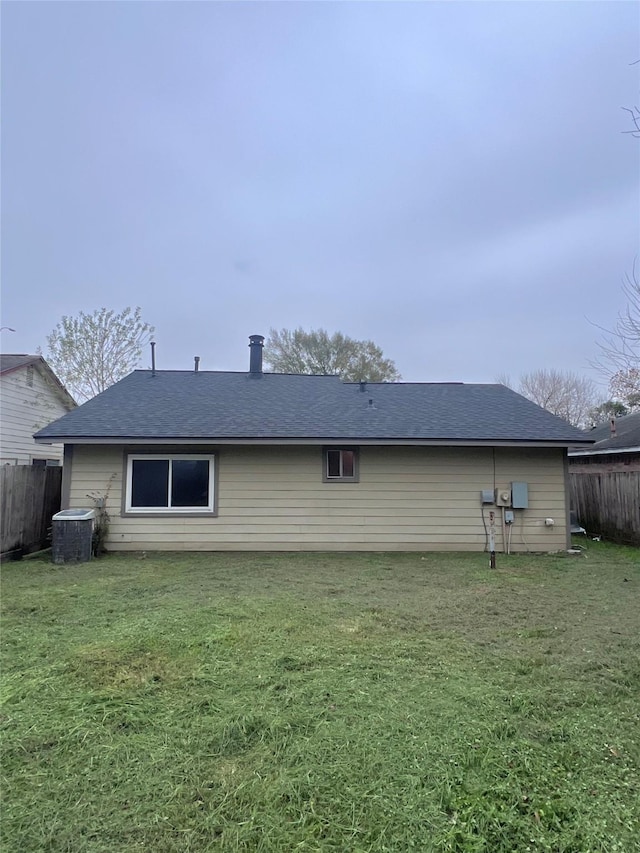 back of house with central air condition unit and a yard