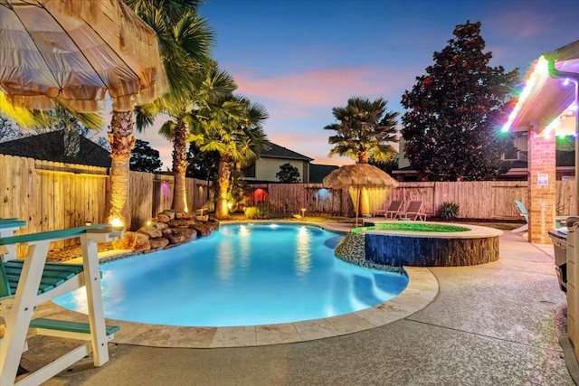 pool at dusk with an in ground hot tub and a patio