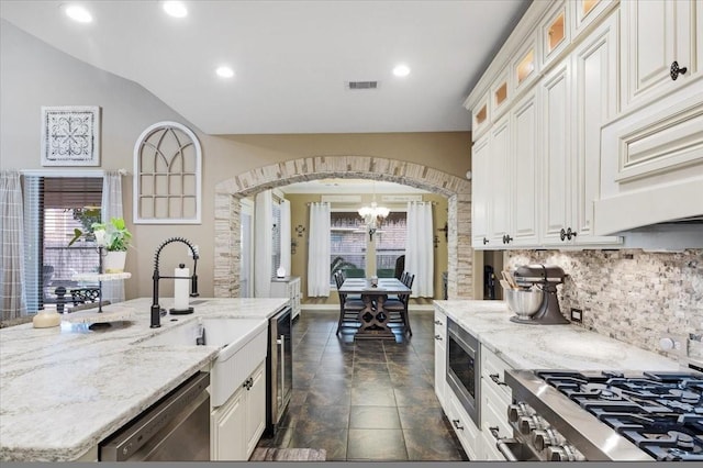 kitchen featuring backsplash, light stone countertops, stainless steel appliances, and a chandelier