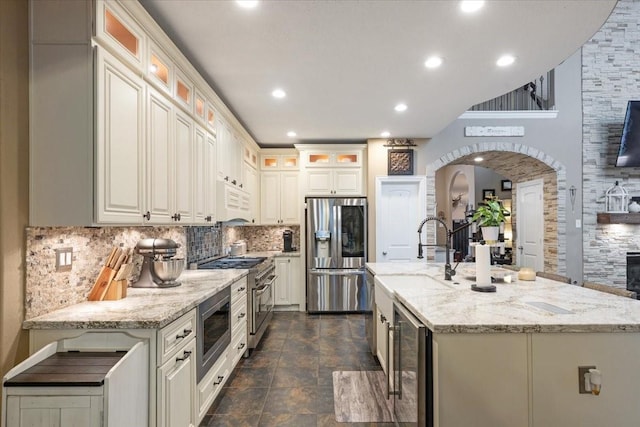 kitchen with wine cooler, light stone counters, sink, and appliances with stainless steel finishes