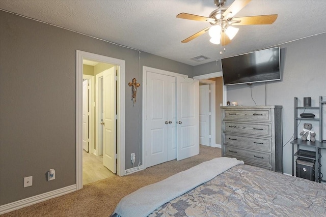 carpeted bedroom with ceiling fan, a closet, and a textured ceiling