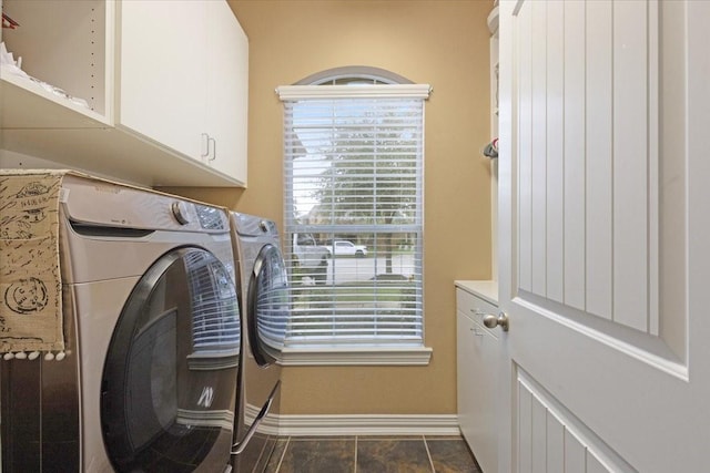 washroom with washing machine and clothes dryer, cabinets, and dark tile patterned flooring