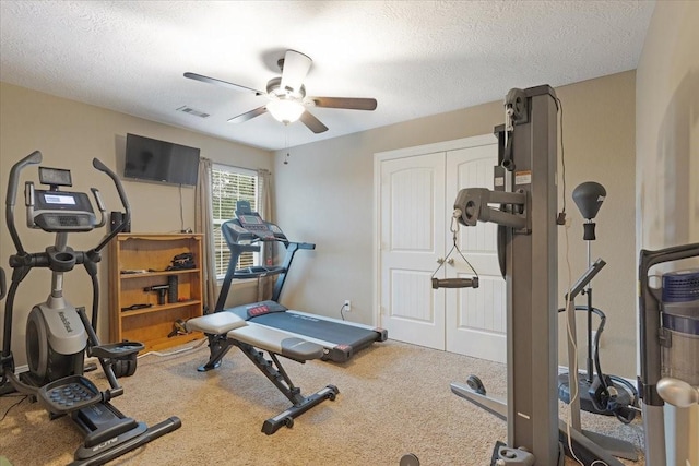 exercise room with a textured ceiling, carpet floors, and ceiling fan