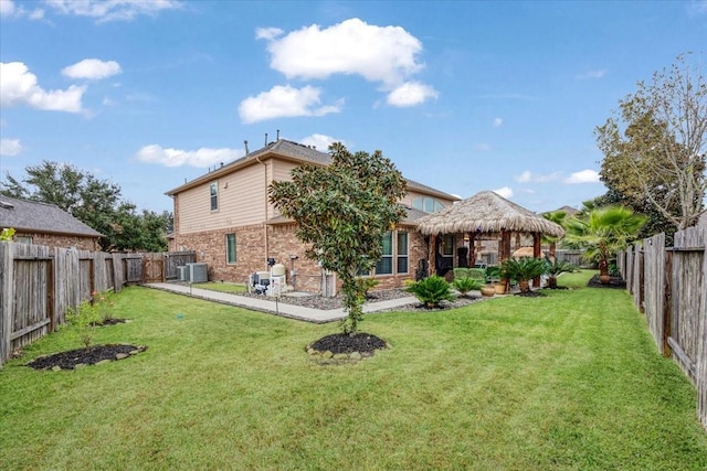 rear view of house featuring a gazebo, central AC unit, and a lawn