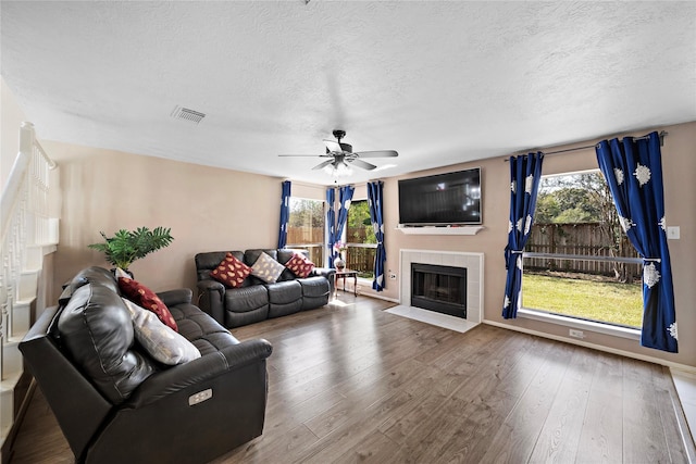 living room with ceiling fan, a healthy amount of sunlight, wood-type flooring, and a fireplace