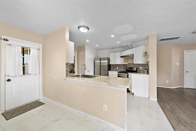 kitchen with kitchen peninsula, white cabinetry, sink, and appliances with stainless steel finishes