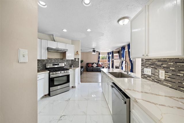 kitchen featuring sink, ceiling fan, light stone countertops, white cabinetry, and stainless steel appliances