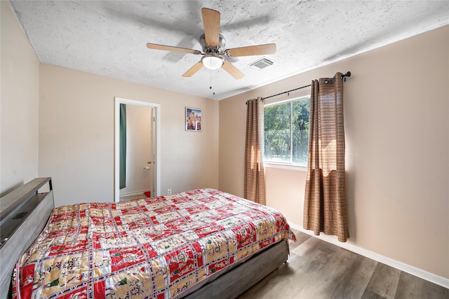 bedroom with hardwood / wood-style floors, ceiling fan, and a textured ceiling