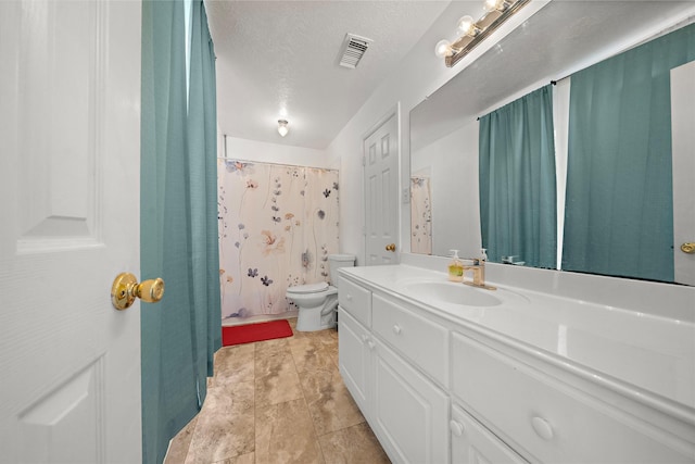 bathroom with vanity, toilet, and a textured ceiling